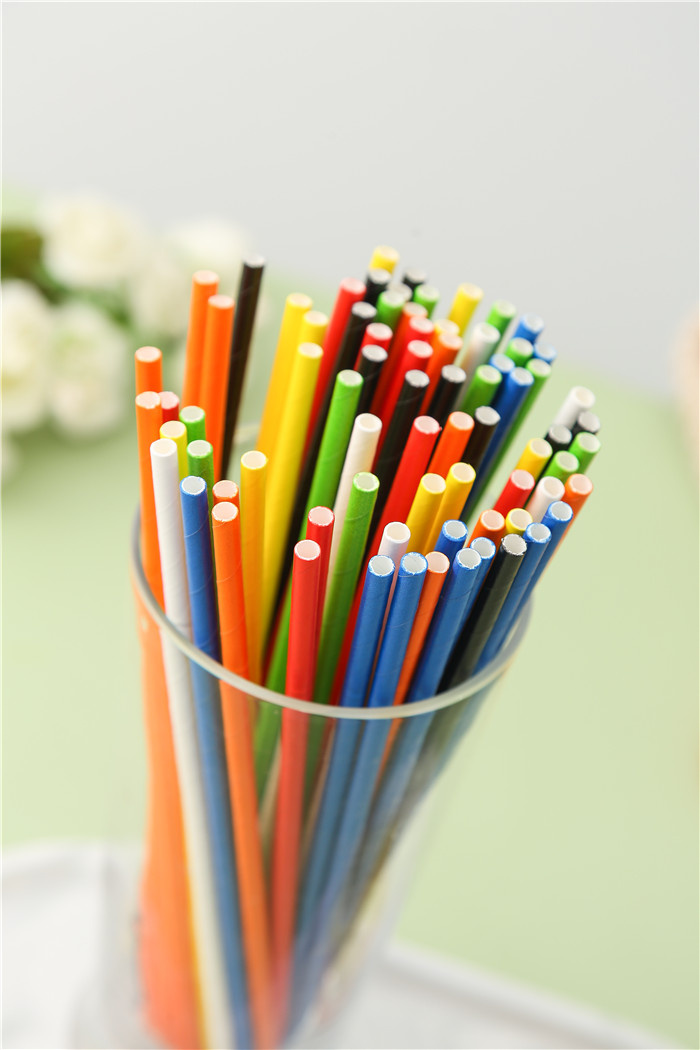 Solid colour paper straws in multiple colours standing in a glass